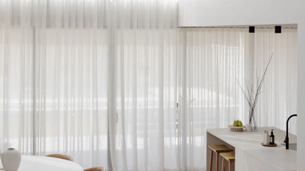 Interior view looking down on living room with sheer curtains over two floors.