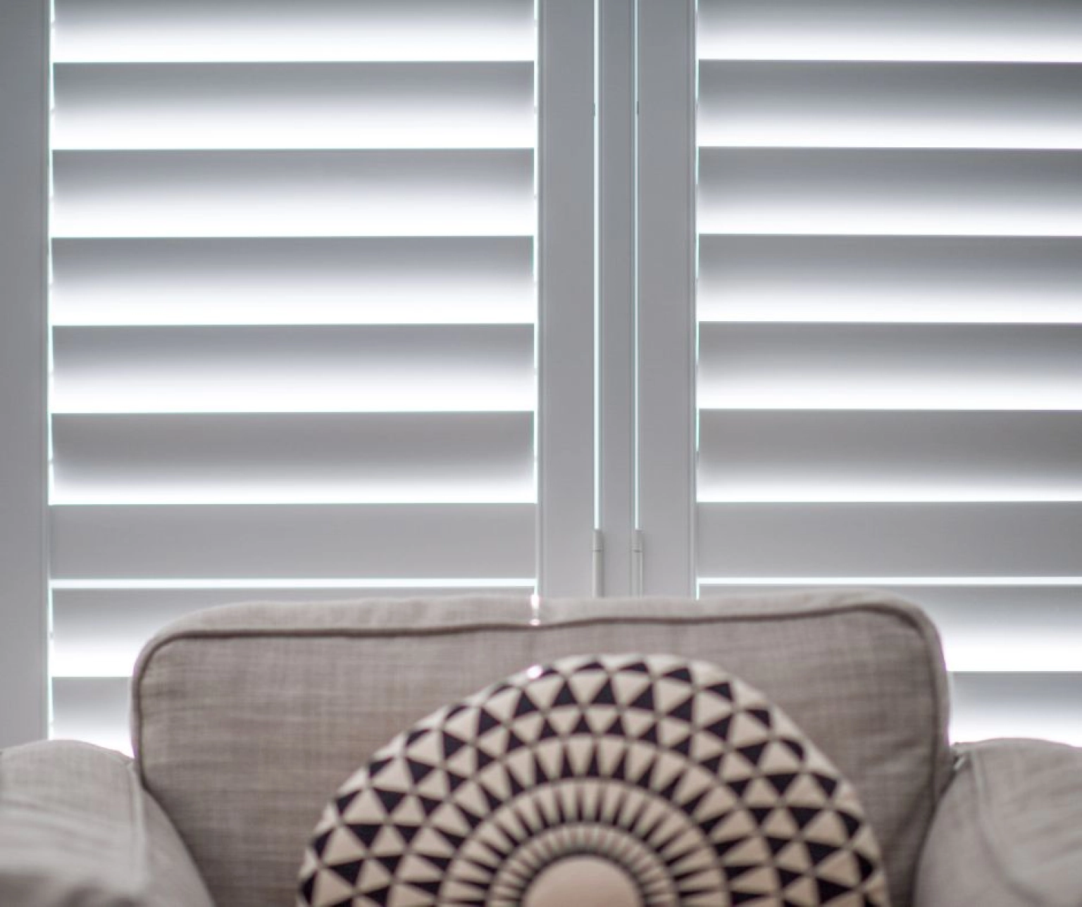 Close up of white plantation shutters behind an armchair